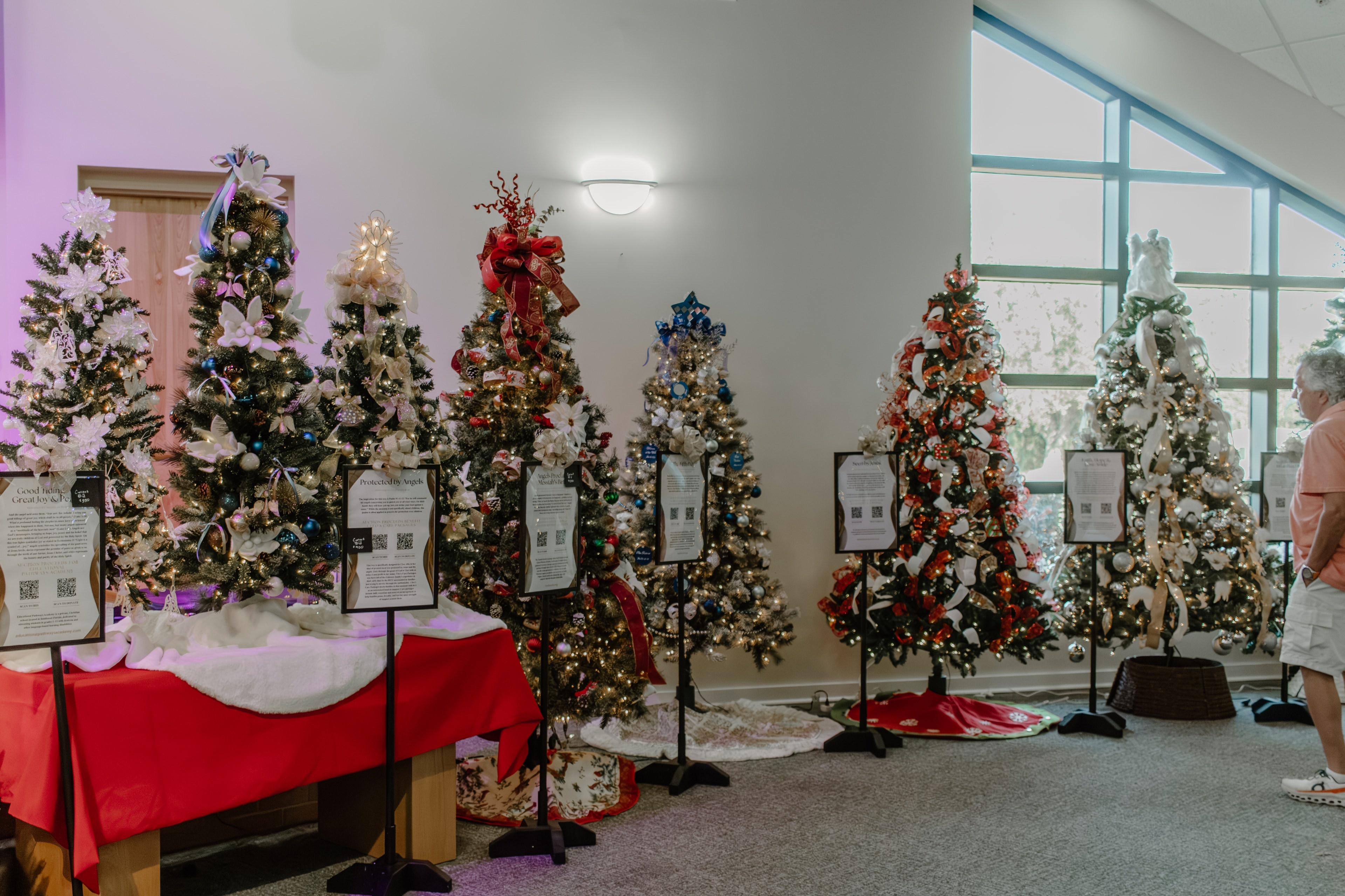 Tree Hall display with five decorated Christmas trees inside the chapel at the Naples Festival of Trees 2025
